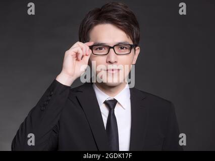 Jeune buisnessman en costume noir et portant des lunettes Banque D'Images