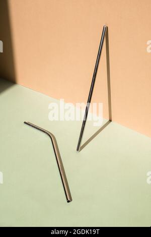 Ensemble de pailles à boire en acier réutilisables de couleur métallique sur fond vert et beige. Concept de style de vie durable. Zéro déchet, articles sans plastique Banque D'Images