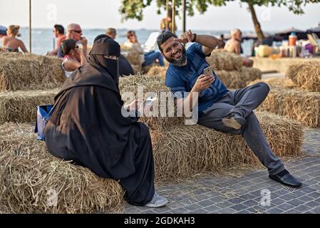 Couple musulman avec une femme en pleine Burka, en utilisant la communication de smartphone tout en se relaxant en vacances. Thaïlande S. E. Asie Banque D'Images