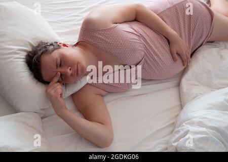 Femme enceinte inquiète dans le lit souffrant d'insomnie Banque D'Images
