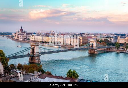 Le Danube avec des bateaux à moteur, le Pont des chaînes et la ligne d'horizon de Pest à Budapest, Hongrie. Photo prise le soir, depuis le château de Buda. Banque D'Images