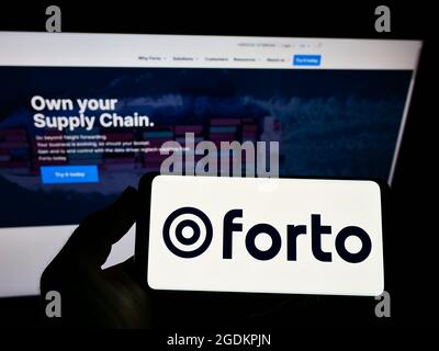 Personne tenant un smartphone avec le logo de la société allemande de logistique Forto GmbH à l'écran devant le site Web. Mise au point sur l'affichage du téléphone. Banque D'Images