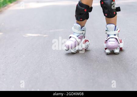 un enfant est en roller dans le parc. jambes de près. Banque D'Images