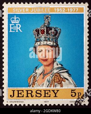 JERSEY - VERS 1977 : un timbre imprimé à Jersey montre la Reine portant la couronne de Saint-Édouard, 25e anniversaire du règne d'Elizabeth II, vers 1977 Banque D'Images