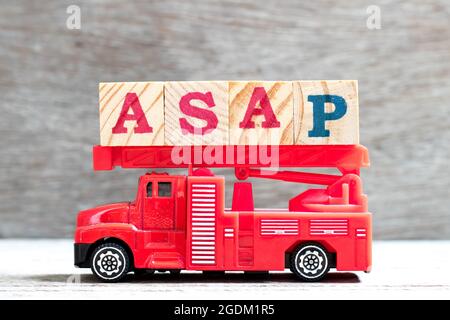 Jouet échelle incendie camion tenir le bloc de lettres dans le mot ASAP (abréviation de Dès que possible) sur fond de bois Banque D'Images