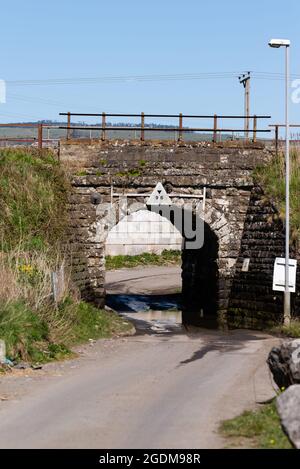 Pont ferroviaire à hauteur limitée sur une route pour le trafic de fichiers uniques Banque D'Images