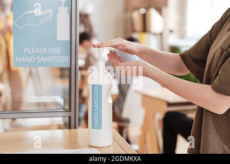 Gros plan d'une femme utilisant un désinfectant pour les mains avant d'entrer dans le bureau Banque D'Images