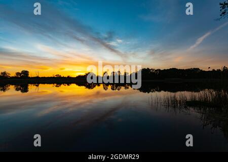 Coucher de soleil sur la rivière, silhouette de la forêt, image miroir dans l'eau Banque D'Images