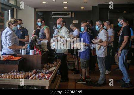 Beyrouth, Liban. 14 août 2021. Les gens font la queue à l'intérieur d'une boulangerie locale pour payer le pain au milieu de graves pénuries de carburant et de coupures d'électricité qui paralysent actuellement le pays, dans le cadre de l'une des pires crises économiques au monde ces derniers temps. Credit: Marwan Naamani/dpa/Alamy Live News Banque D'Images