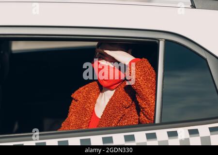 Une jeune femme passager prend un trajet en voiture de taxi pendant la quarantaine pandémique du coronavirus. Femme portant un masque médical stérile. Concept de la distance sociale et de la sécurité sanitaire dans les transports Banque D'Images