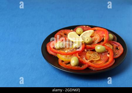 Concept de nourriture savoureuse avec carpaccio de tomate sur fond bleu Banque D'Images