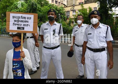 Kolkata, Inde. 14 août 2021. Un petit manifestant tient un écriteau devant une police pendant le rassemblement de protestation contre le CNRC, CAA à Kolkata. (Photo de Sudipta Das/Pacific Press) crédit: Pacific Press Media production Corp./Alay Live News Banque D'Images