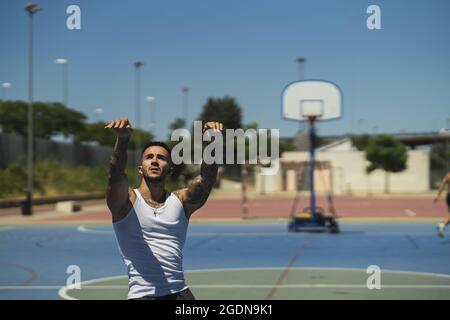 Jeune homme musclé jouant au basket-ball sur l'aire de jeux Banque D'Images