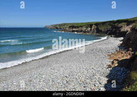 La plage de pierres et les falaises dans la baie à Aber Mawr, Pembrokeshire, pays de Galles, Royaume-Uni Banque D'Images