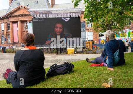 Édimbourg, Écosse, Royaume-Uni. 14 août 2021. Vues sur le jour d'ouverture du Festival International du livre d'Édimbourg à un nouveau lieu au Edinburgh College of Art. Ayant quitté son ancien site aux jardins de Charlotte Square, le Festival du livre s'est déplacé dans une cour au Edinburgh College of Art. Le nombre de visiteurs était probablement faible à l'heure du déjeuner en raison de de nombreux événements sont déplacés vers des diffusions en ligne. Photo : le grand écran de la cour montre des interviews en direct avec des auteurs. Iain Masterton/Alamy Live News. Banque D'Images