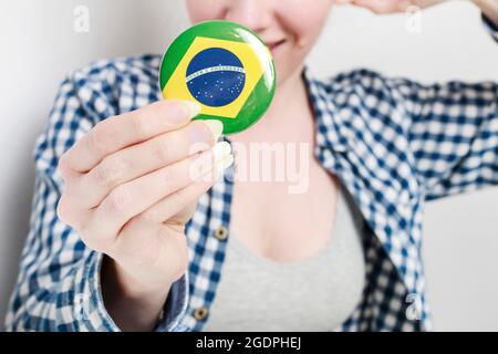 Drapeau du Brésil imprimé sur le badge de bouton, tenu par une femme dans ses belles mains. Banque D'Images