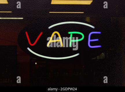 Enseigne à motif de Vape au néon dans la fenêtre du magasin de fumée à la pluie, accent sur les lettres au néon Banque D'Images
