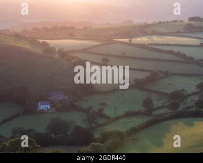 Lever du soleil le matin brumeux sur les collines et les terres agricoles de Dartmoor Banque D'Images