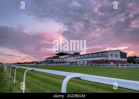 Exeter Racecourse, Devon, Angleterre. Samedi 14 août 2021. Météo Royaume-Uni. Après une journée de soleil d'été à Devon, le célèbre champ de courses National Hunt d'Exeter est calme et serein tandis que le soleil se couche derrière le stand principal. En revanche, la A38, très fréquentée, qui longe le parcours de Haldon Hills, est toujours occupée à faire des vacanciers jusqu'à la côte. Terry Mathews/Alamy Live News. Banque D'Images