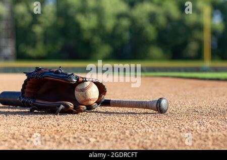 Base-ball dans un mitt avec une batte noire, vue de mise au point sélective à faible angle sur un terrain de base-ball Banque D'Images