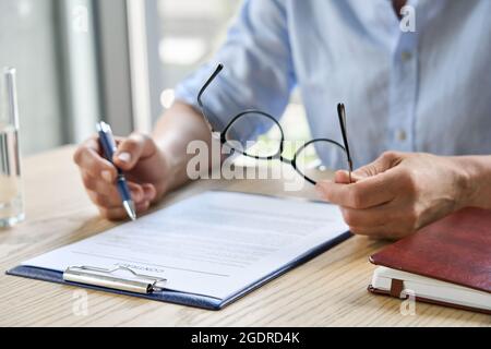 Une femme d'affaires avocate a lu le contrat de partenariat à la table tenant des lunettes. Gros plan Banque D'Images