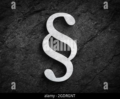Symbole de paragraphe en pierre blanche pour la loi et l'ordre sur fond de mur en pierre sombre Banque D'Images