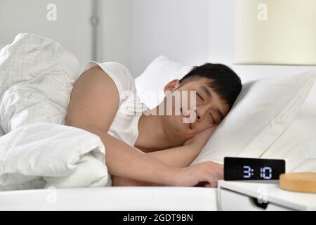 Beau jeune homme asiatique dormant au lit Banque D'Images