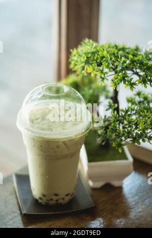 Thé vert matcha à bulles glacé avec bonsaï artificiel dans un café de style japonais Banque D'Images