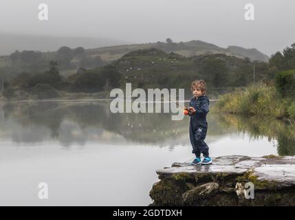 Gougane Barra, Cork, Irlande. 14 août 2021. Lors d'une journée brumeuse à West Cork, un garçon de quatre ans essaie sa nouvelle canne à pêche sur le lac à Gougane Barra, Co. Cork, Irlande. - photo; David Creedon / Alamy Live News Banque D'Images