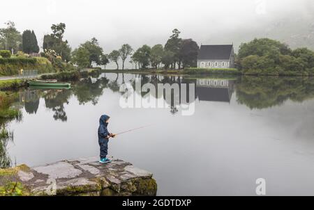 Gougane Barra, Cork, Irlande. 14 août 2021. Lors d'une journée brumeuse à West Cork, un garçon de quatre ans essaie sa nouvelle canne à pêche sur le lac à Gougane Barra, Co. Cork, Irlande. - photo; David Creedon / Alamy Live News Banque D'Images