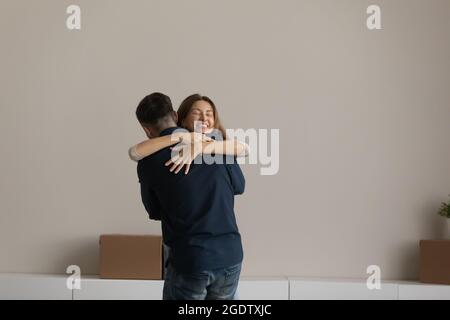 Un couple heureux debout dans une pièce non meublée qui se fait une joie de célébrer le jour de la réinstallation Banque D'Images