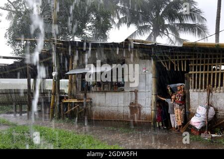 Les jeunes de la tribu indigène Blaan se réfugient à l'abri de la pluie tropicale. Village de Maligo Blaan, Brgy. Maligo. Mindanao Island, Philippines Banque D'Images