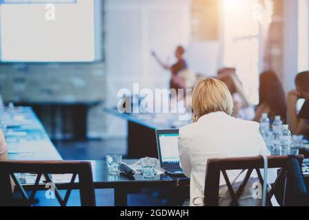 Femme d'affaires dans une veste blanche assise à une table lors d'une conférence. Banque D'Images