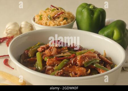 Bébé maïs manchurien. Maïs frit croustillant dans une sauce manchurienne avec poivrons et oignons. Servi avec du riz frit. Prise de vue sur bac blanc Banque D'Images