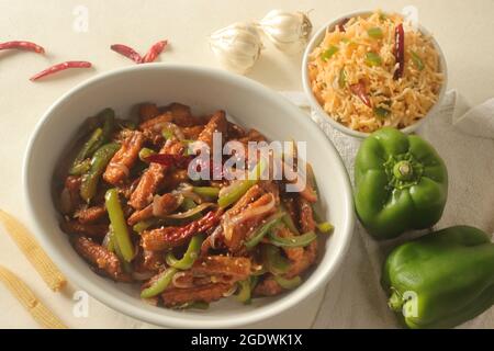 Bébé maïs manchurien. Maïs frit croustillant dans une sauce manchurienne avec poivrons et oignons. Servi avec du riz frit. Prise de vue sur bac blanc Banque D'Images