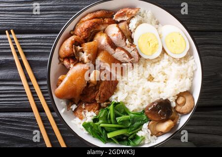 Le ragoût de la jambe de porc sur le riz ou kao ka moo est la quintessence de la cuisine thaïlandaise de rue dans le bol sur la table. Vue horizontale du dessus Banque D'Images