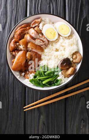 Cuisine thaïlandaise chinoise riz au jasmin Khao Kha Moo avec oeufs bouillis de jambe de porc, champignons de près dans le bol sur la table. Vue verticale du dessus Banque D'Images