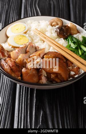 Cuisine thaïlandaise chinoise riz au jasmin Khao Kha Moo avec oeufs bouillis de jambe de porc, champignons de près dans le bol sur la table. Verticale Banque D'Images