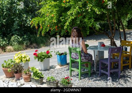 Femme reposant sur des chaises colorées parmi des fleurs dans le village d'Uçmakdere le 25 juillet 2021. Banque D'Images