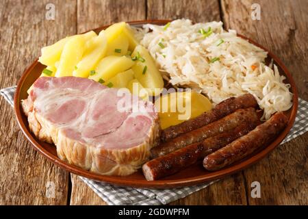 Saucisse traditionnelle allemande fumée, col de porc Kassler, choucroute, moutarde et pommes de terre bouillies dans l'assiette sur la table. Horizontale Banque D'Images