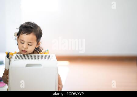 Un gros plan d'une petite fille thaïlandaise mignonne à côté d'un purificateur d'air Banque D'Images