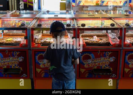 08-12-2021 Portsmouth, Hampshire, Royaume-Uni UN petit garçon jouant les jeux d'arcade de coin Push dans une arcade de divertissement Banque D'Images
