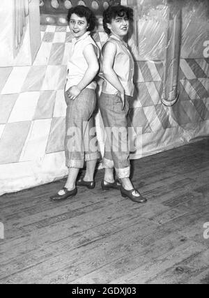 1957, historique, deux jeunes femmes performant dans leurs costumes - les jeans se sont présentés aux ankes et les chemisiers sans manches - apparaissant dans la pantomine Aladdin, une histoire basée sur un conte populaire du Moyen-Orient, debout sur la scène pour leur photo, Angleterre, Royaume-Uni. Les jeans à revers ou roulé sont devenus à la mode en Grande-Bretagne au début du rock and roll, quand le rockabilly est devenu populaire. Banque D'Images
