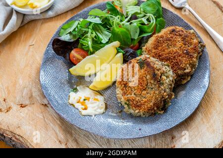 Gâteaux de poisson sardine avec salade de feuilles vertes, mayonnaise à l'ail et quartiers de citron Banque D'Images