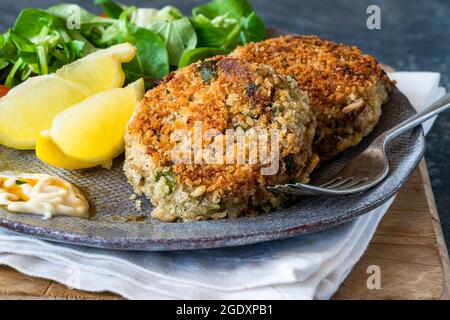 Gâteaux de poisson sardine avec salade de feuilles vertes, mayonnaise à l'ail et quartiers de citron Banque D'Images