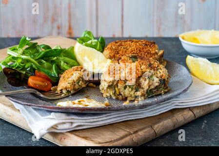 Gâteaux de poisson sardine avec salade de feuilles vertes, mayonnaise à l'ail et quartiers de citron Banque D'Images