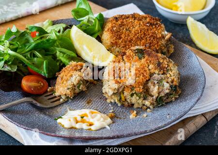 Gâteaux de poisson sardine avec salade de feuilles vertes, mayonnaise à l'ail et quartiers de citron Banque D'Images