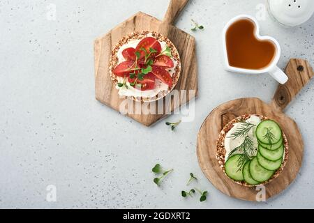 Gâteau au sarrasin croustillant sans gluten avec fromage à la crème, radis rouge, tomates et micro-vert pour un petit déjeuner sain sur fond de pierre grise. Voir fr Banque D'Images