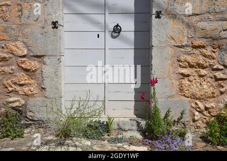 Ancienne maison rurale porte en bois grise avec un knocker en fer sur un mur en pierre fait à la main à Stemnitsa, Arcadia Péloponnese, Grèce. Banque D'Images