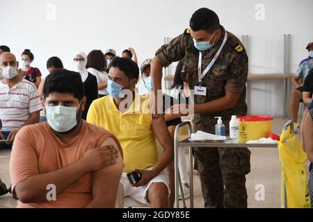 Tunis, Tunisie. 15 août 2021. Un membre du personnel médical militaire tunisien administre une dose de vaccin COVID-19 à un bénéficiaire dans un centre de vaccination à Tunis, Tunisie, le 15 août 2021. La deuxième journée nationale tunisienne de vaccination contre le COVID-19 a débuté dimanche dans les 24 provinces du pays pour les citoyens âgés de 18 à 39 ans. Au total, 405 centres de vaccination, répartis dans tout le pays, ont été mis en place exclusivement pour cette journée portes ouvertes. Crédit: Adel Ezzine/Xinhua/Alamy Live News Banque D'Images